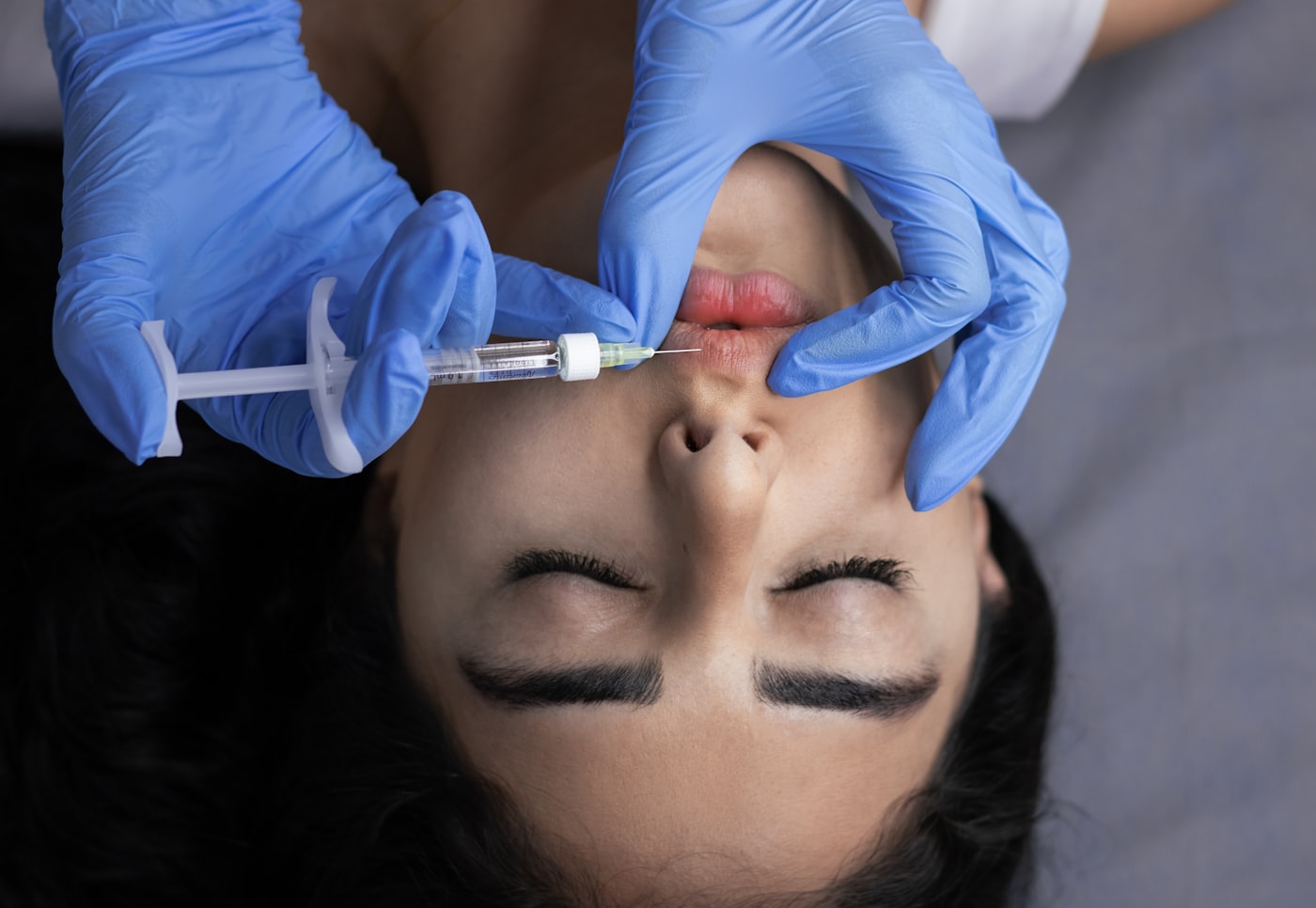 Kosmetische Prozedur an den Lippen in Nahaufnahme, Master mit Handschuhen