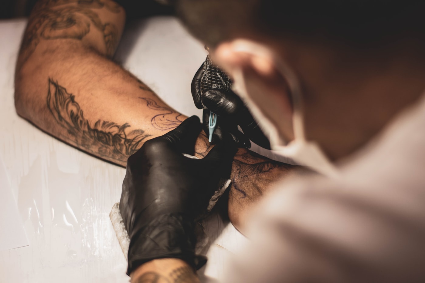 Master trägt Betäubungscreme auf die Haut des Kunden vor der Tattoo-Sitzung auf